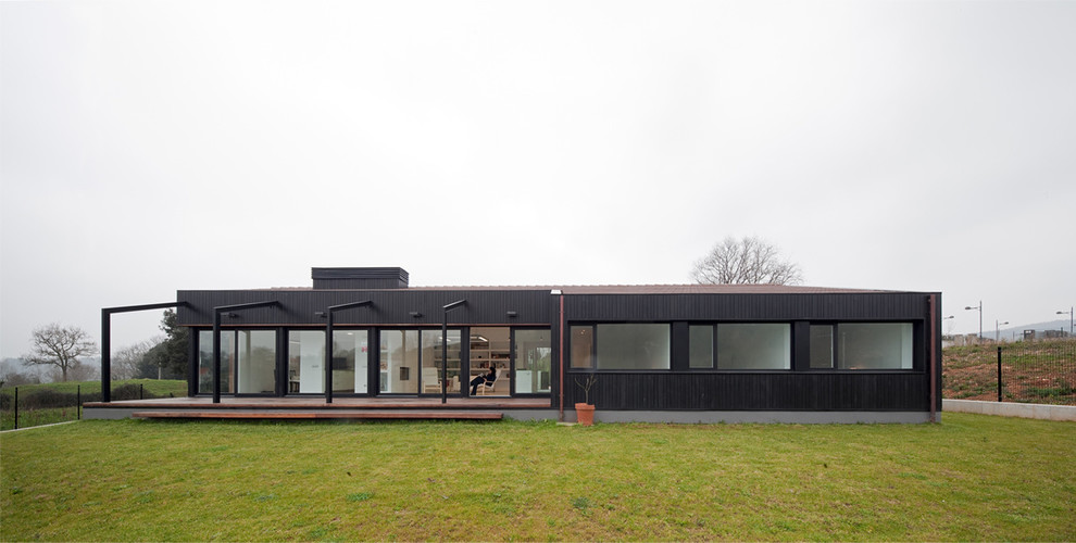 Diseño de fachada negra moderna con revestimiento de metal y tejado a dos aguas