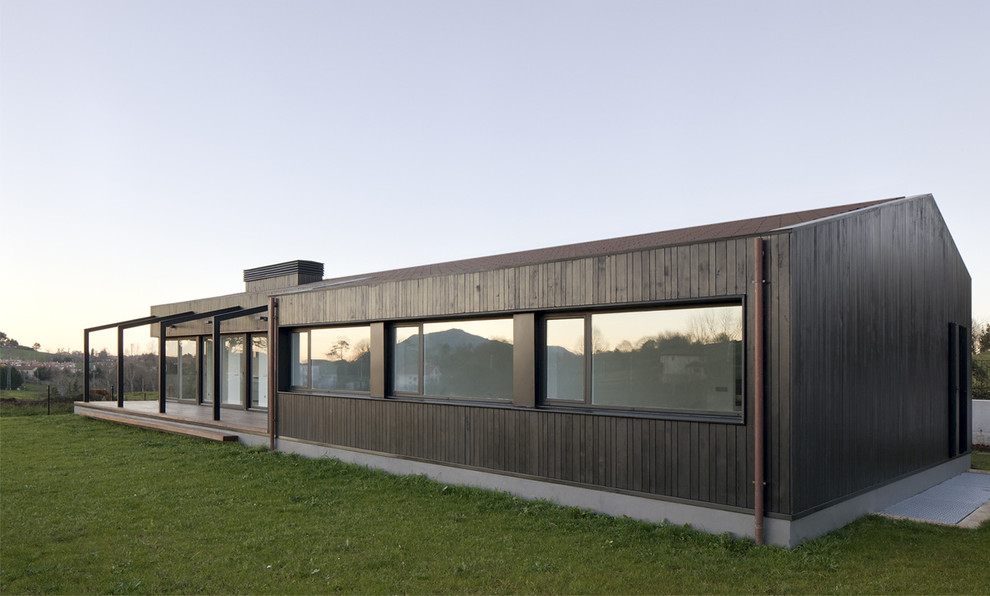 Imagen de fachada negra moderna de una planta con revestimiento de metal y tejado a dos aguas