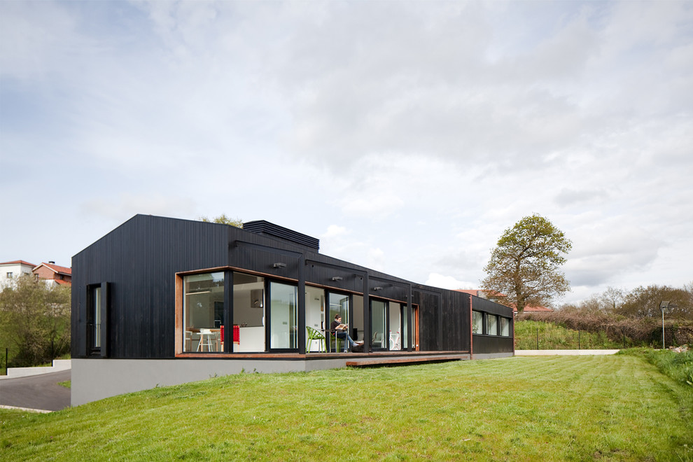 Cette image montre une façade de maison métallique et noire minimaliste de plain-pied avec un toit à deux pans.