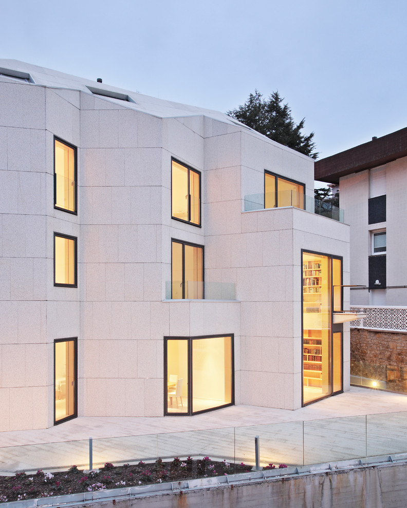 Idée de décoration pour une grande façade de maison beige design en pierre à deux étages et plus.