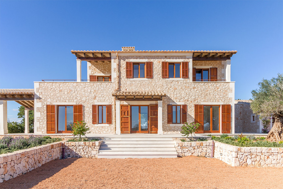 Ejemplo de fachada de casa mediterránea de dos plantas con revestimiento de piedra y tejado de teja de barro