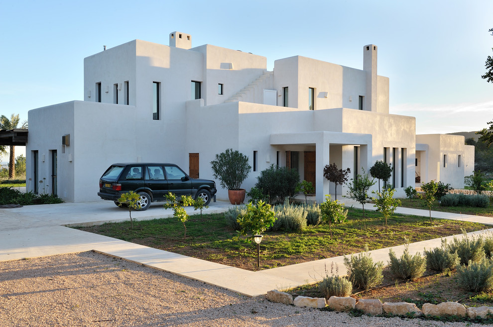 Diseño de fachada blanca mediterránea de tamaño medio de dos plantas con revestimiento de estuco y tejado plano