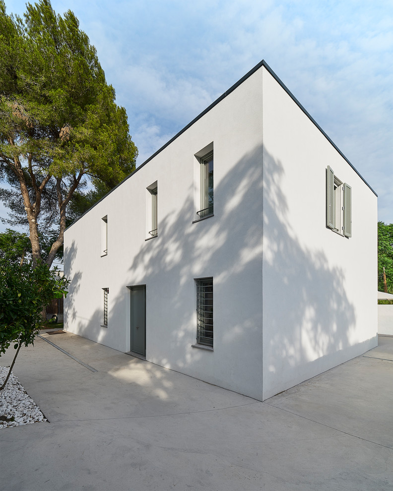 Imagen de fachada de casa blanca mediterránea de tamaño medio de dos plantas con revestimiento de aglomerado de cemento, tejado plano y tejado de varios materiales