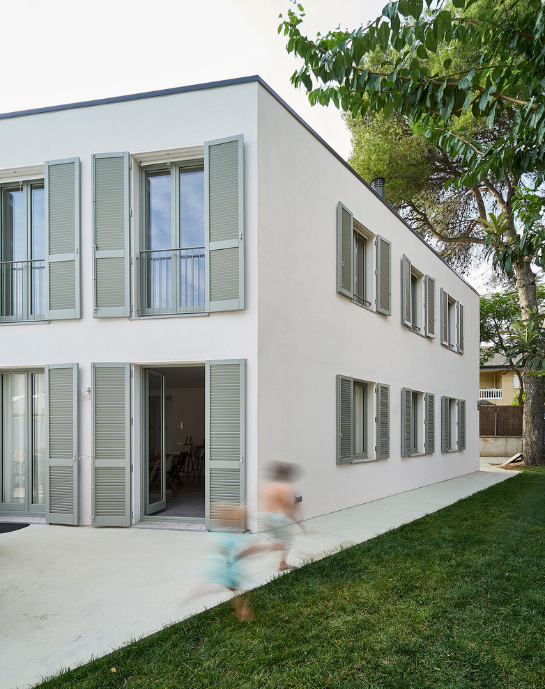Пример оригинального дизайна: двухэтажный, белый частный загородный дом среднего размера в средиземноморском стиле с облицовкой из ЦСП, плоской крышей и крышей из смешанных материалов