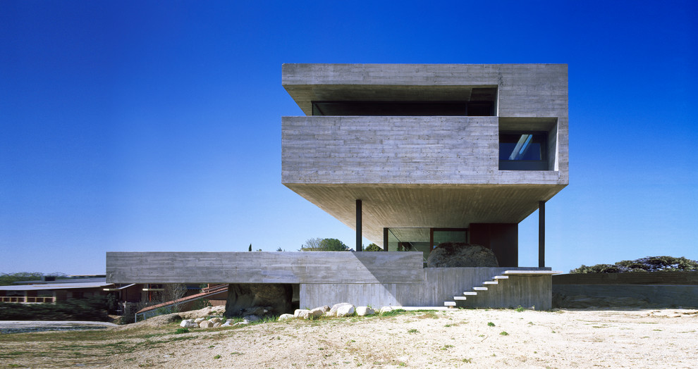 Bild på ett mycket stort funkis grått betonghus, med platt tak och tre eller fler plan