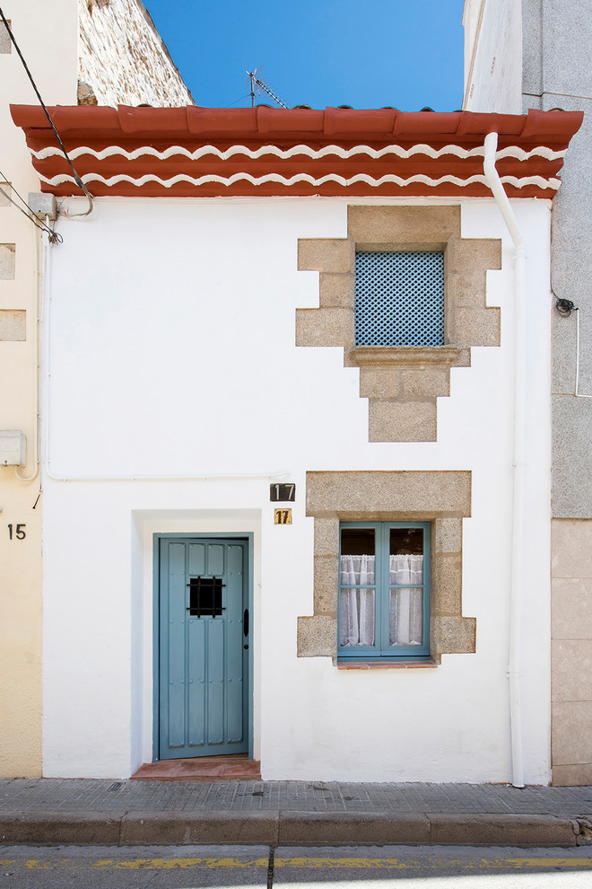 Kleines, Zweistöckiges Mediterranes Haus mit Putzfassade, weißer Fassadenfarbe, Pultdach und Ziegeldach in Barcelona