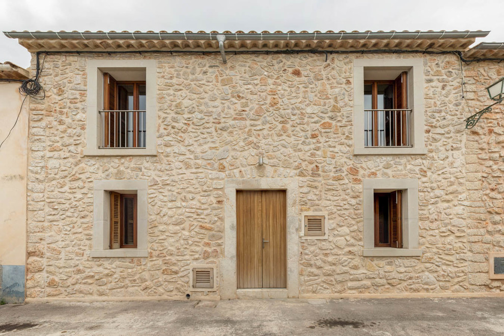Ispirazione per la facciata di una casa marrone mediterranea a due piani di medie dimensioni con rivestimento in pietra e tetto a capanna