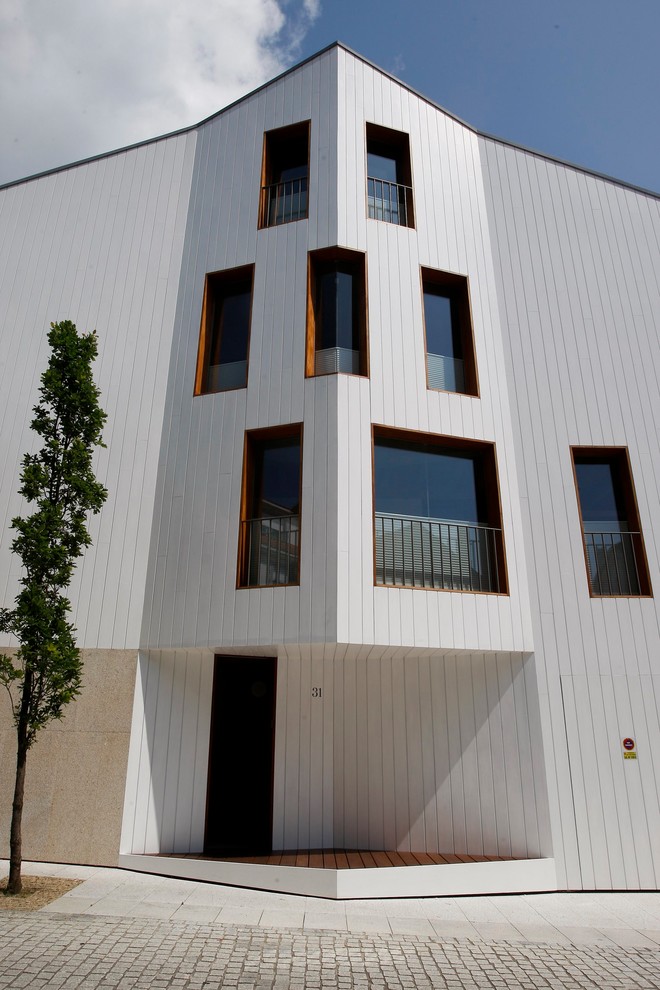 Immagine della villa piccola bianca contemporanea a tre piani con rivestimento in legno e copertura in metallo o lamiera