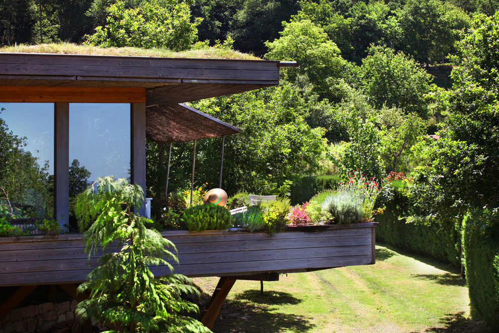 На фото: маленький, одноэтажный, деревянный, разноцветный частный загородный дом в восточном стиле с плоской крышей и зеленой крышей для на участке и в саду с