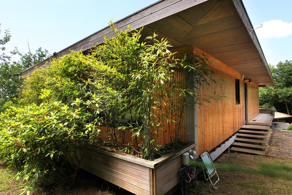 Пример оригинального дизайна: маленький, одноэтажный, деревянный, разноцветный частный загородный дом в восточном стиле с плоской крышей и зеленой крышей для на участке и в саду