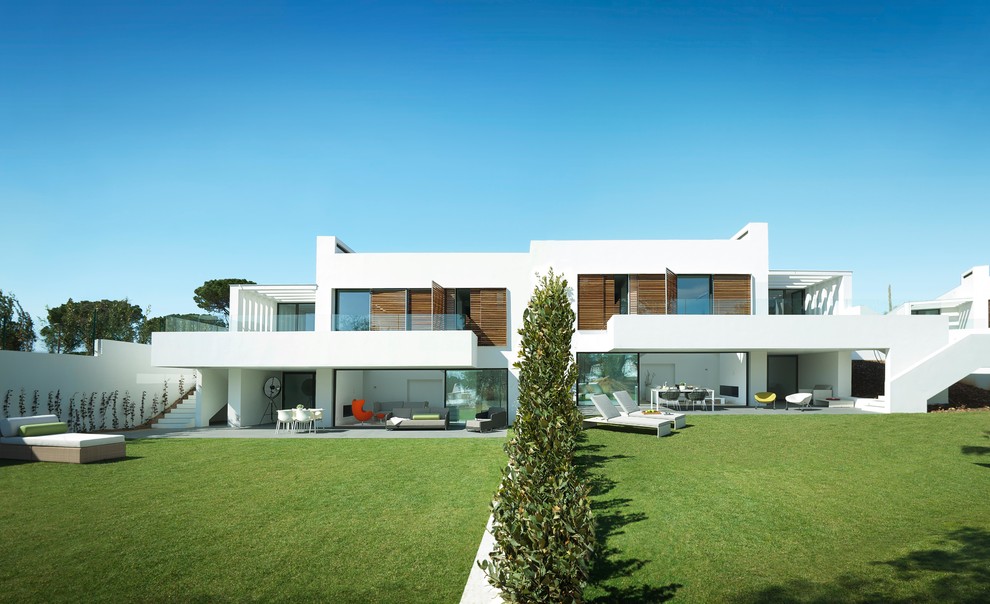 Idée de décoration pour une façade de maison blanche design en stuc de taille moyenne et à un étage avec un toit plat.