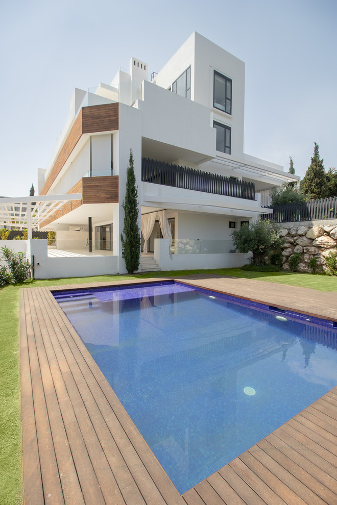Design ideas for a white contemporary detached house in Malaga with three floors and a flat roof.