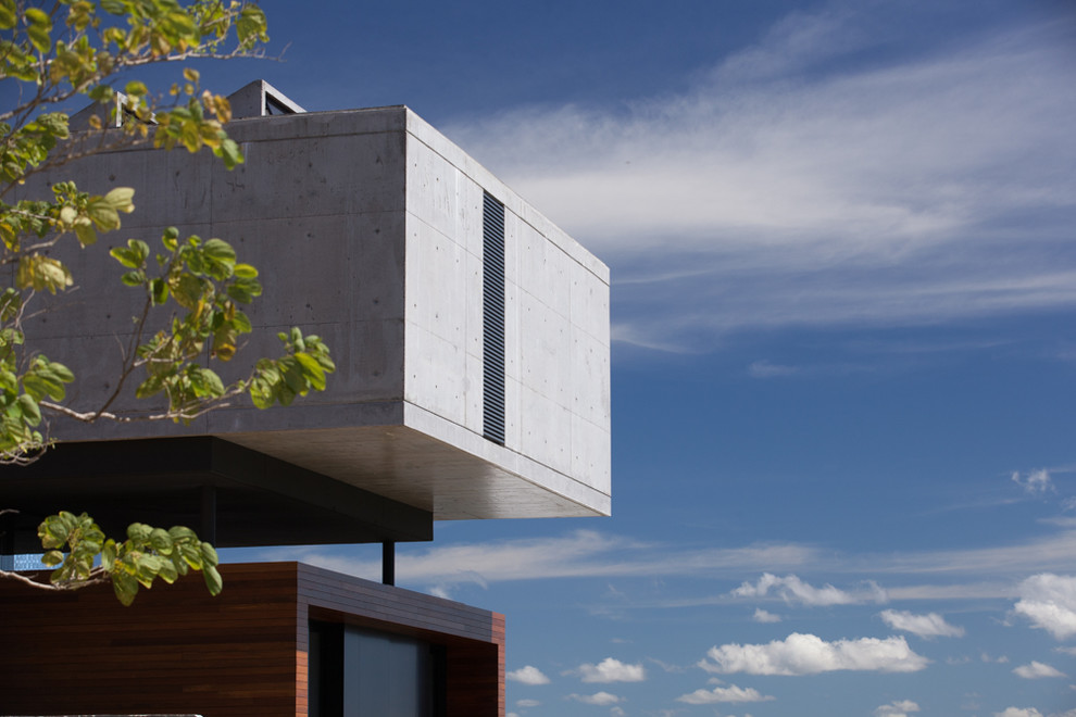 Inspiration pour une grande façade de maison grise minimaliste en béton à deux étages et plus avec un toit plat et un toit mixte.