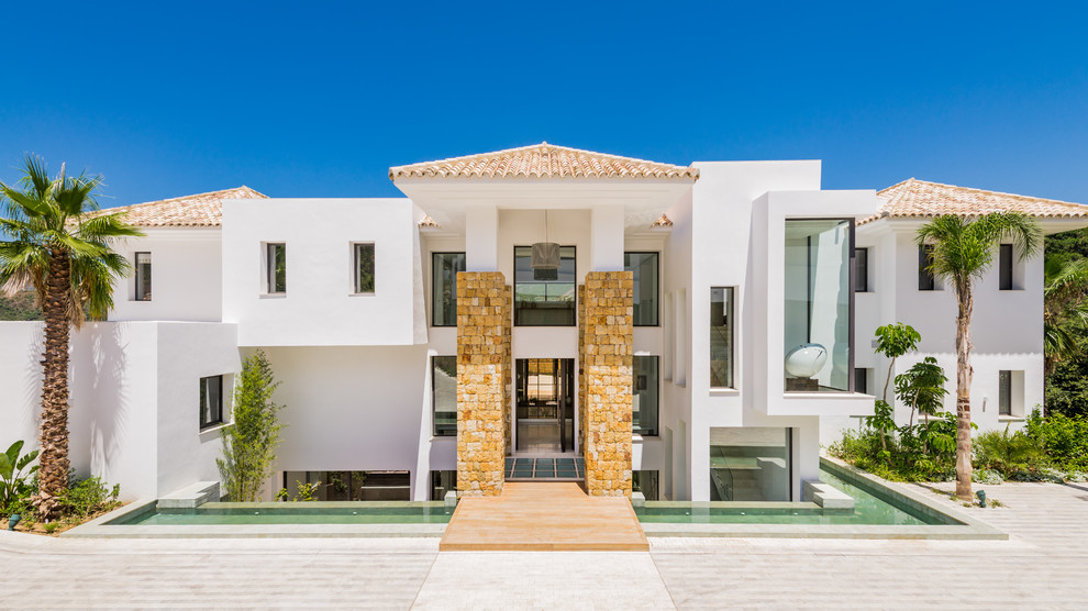 Cette photo montre une façade de maison blanche méditerranéenne à deux étages et plus avec un toit à quatre pans et un toit en tuile.