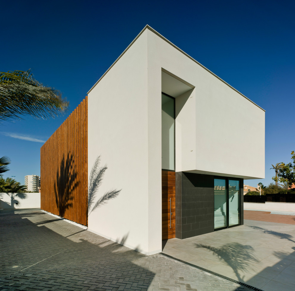 Diseño de fachada de casa blanca contemporánea de dos plantas con revestimientos combinados y tejado plano