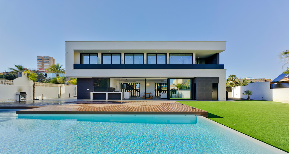 Imagen de fachada de casa blanca contemporánea de dos plantas con revestimientos combinados y tejado plano