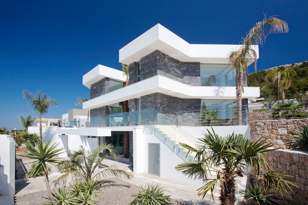 Пример оригинального дизайна: трехэтажный, серый дом в современном стиле с облицовкой из камня и плоской крышей