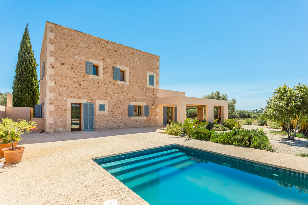 Diseño de fachada beige mediterránea de tamaño medio de dos plantas con revestimiento de piedra y tejado plano