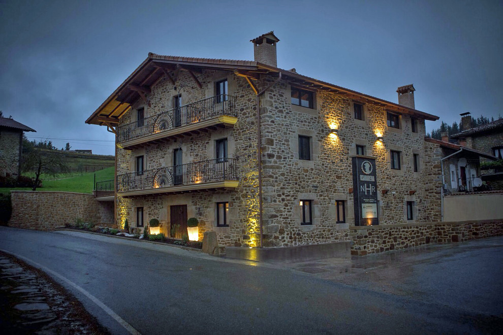Inspiration for a medium sized rustic house exterior in Bilbao with three floors, stone cladding and a pitched roof.