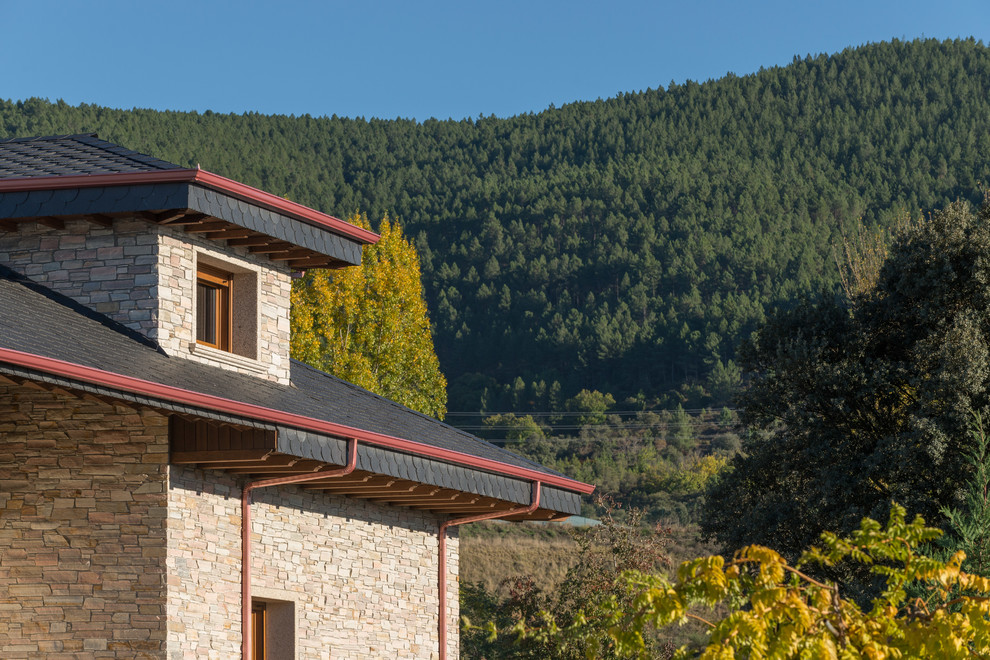 Mittelgroßes Rustikales Einfamilienhaus mit Steinfassade, pinker Fassadenfarbe und Satteldach in Sonstige