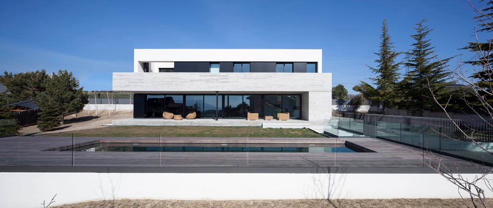Cette image montre une façade de maison grise design en béton de taille moyenne et à un étage avec un toit plat.