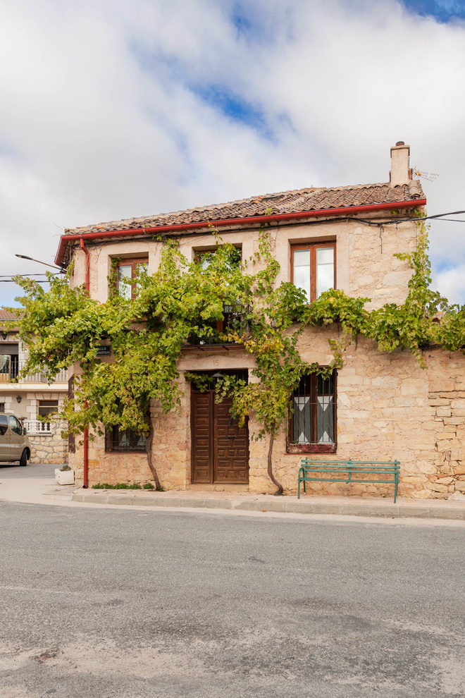 Foto de fachada de casa beige, mediterránea, de dos plantas, con revestimiento de piedra, tejado a cuatro aguas y tejado de teja de barro
