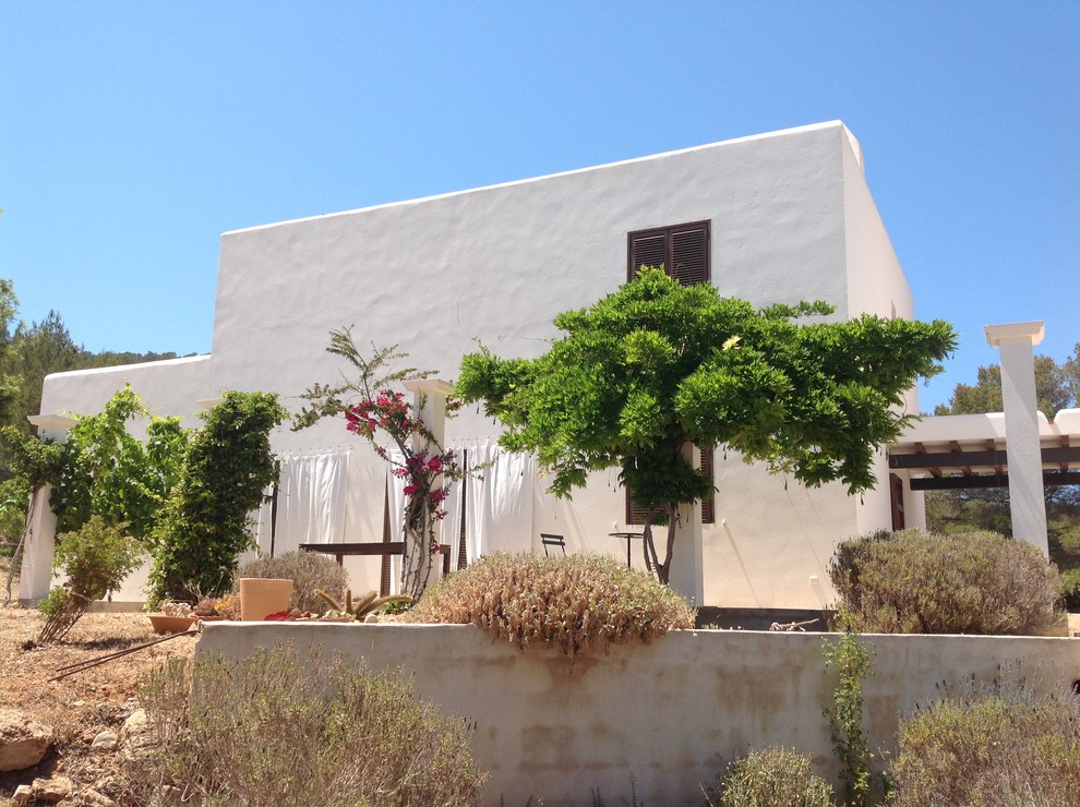 Immagine della facciata di una casa piccola bianca mediterranea a due piani con rivestimenti misti e tetto piano