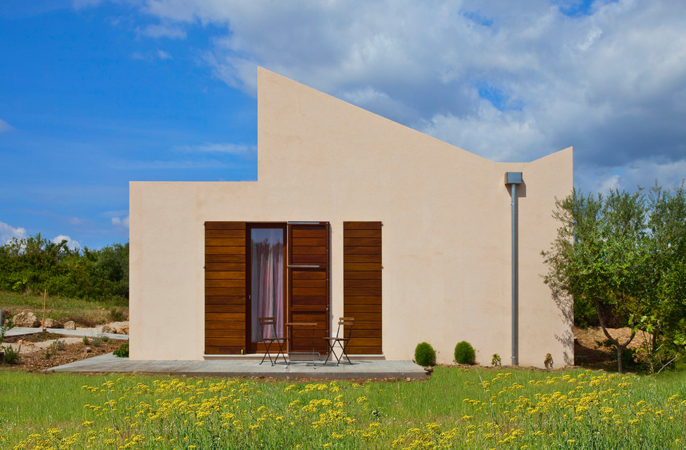 Идея дизайна: маленький, двухэтажный, бежевый дом в современном стиле с облицовкой из цементной штукатурки и односкатной крышей для на участке и в саду