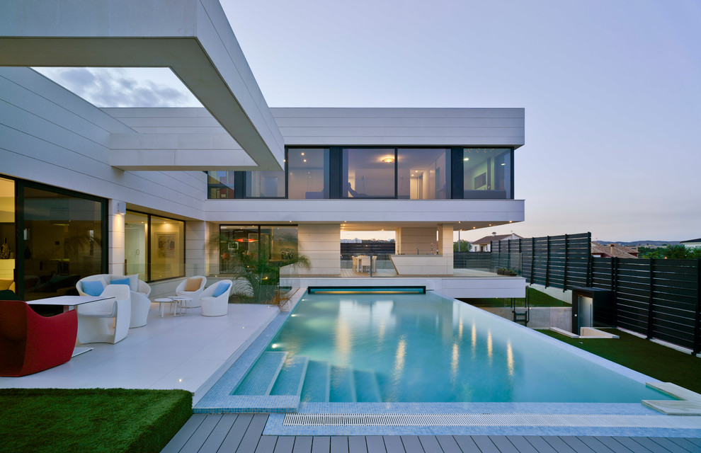 Стильный дизайн: большой, двухэтажный, бежевый дом в стиле модернизм с облицовкой из камня и плоской крышей - последний тренд