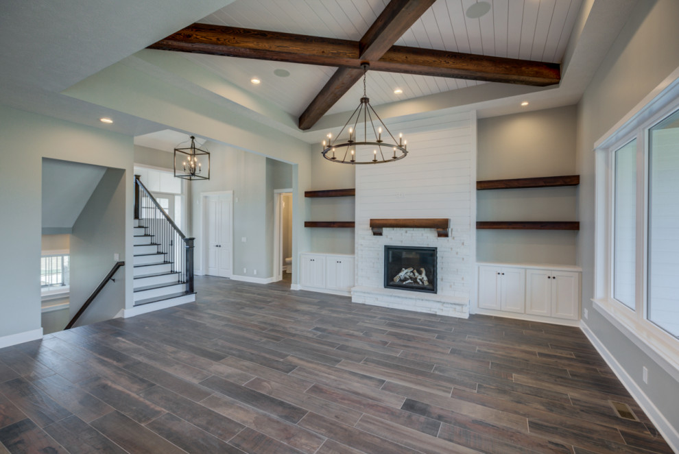 This is an example of a large games room in Omaha with a stone fireplace surround, no tv, exposed beams and tongue and groove walls.