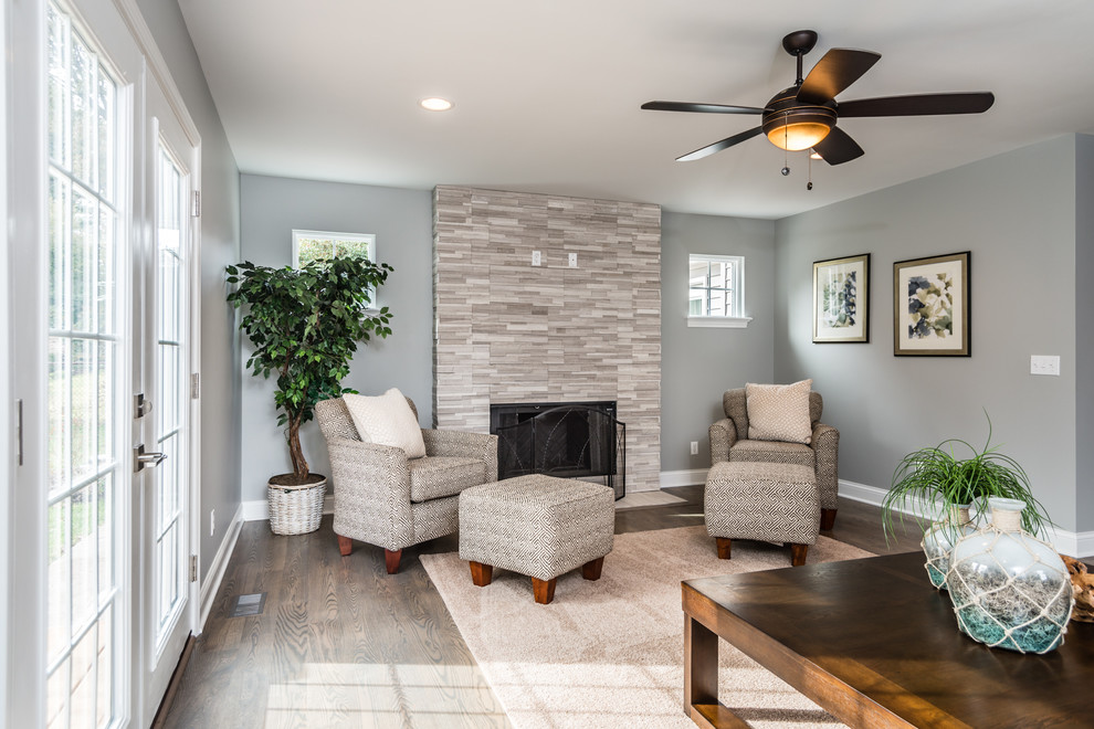 Foto de sala de estar abierta contemporánea grande con paredes grises, suelo de madera en tonos medios, todas las chimeneas, marco de chimenea de piedra y televisor colgado en la pared