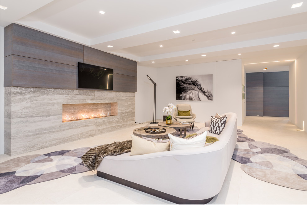 Imagen de sala de estar contemporánea extra grande con paredes blancas, chimenea lineal, marco de chimenea de piedra, televisor colgado en la pared, suelo blanco y alfombra