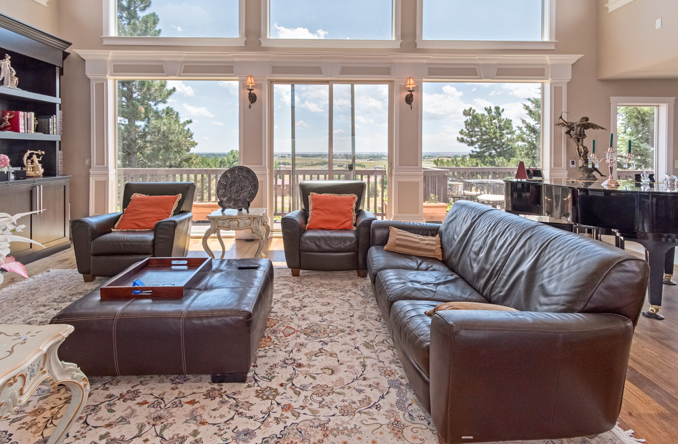 На фото: открытая гостиная комната среднего размера в стиле неоклассика (современная классика) с бежевыми стенами, паркетным полом среднего тона, горизонтальным камином, фасадом камина из камня, телевизором на стене, бежевым полом и коричневым диваном с