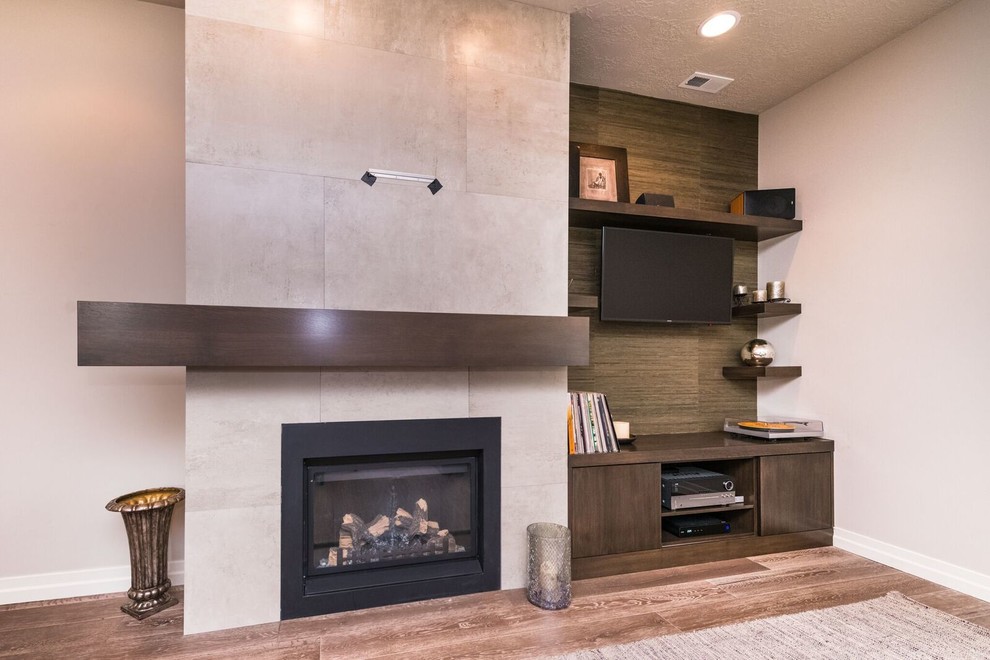 Exemple d'une salle de séjour éclectique de taille moyenne et ouverte avec un mur beige, un sol en bois brun, une cheminée standard, un manteau de cheminée en carrelage et un téléviseur encastré.