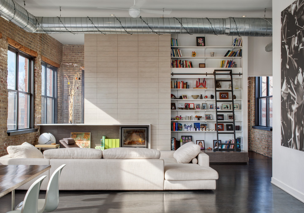 Foto di un grande soggiorno industriale aperto con pareti bianche, libreria, pavimento in cemento, nessun camino, parete attrezzata e pavimento grigio