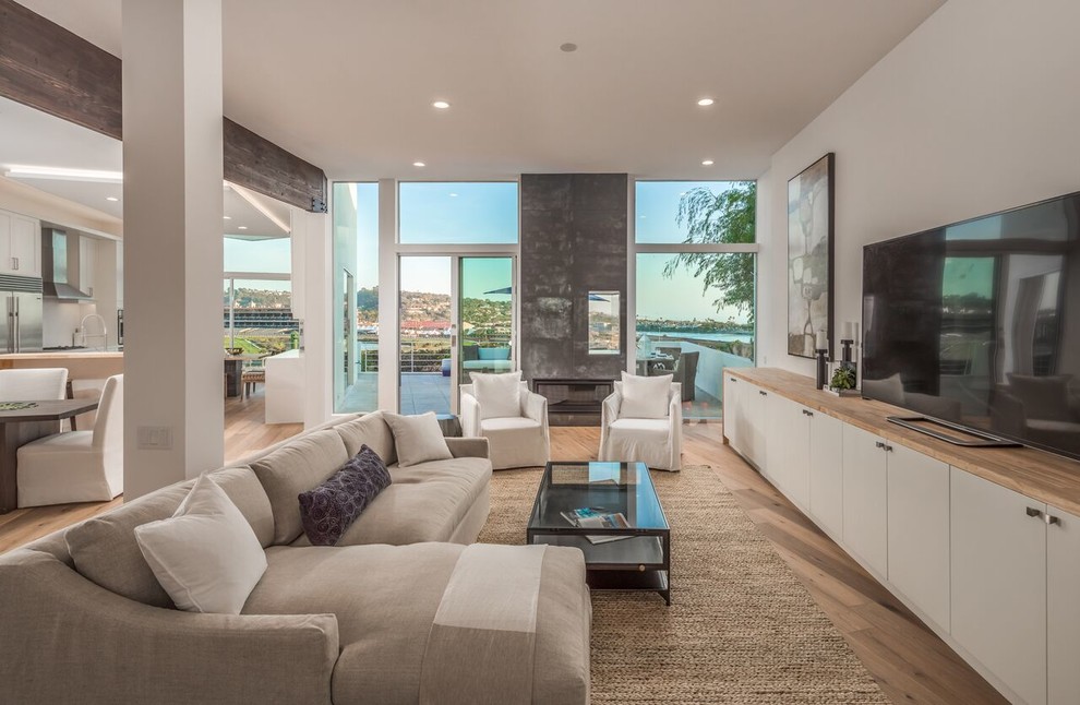 Offenes Maritimes Wohnzimmer ohne Kamin mit weißer Wandfarbe, hellem Holzboden und freistehendem TV in San Diego