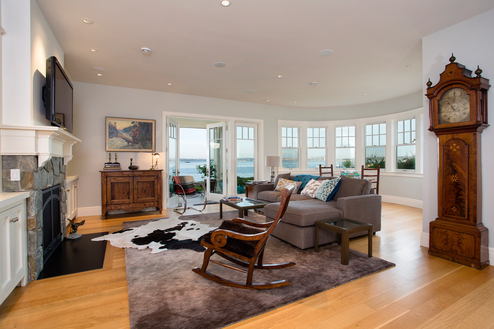 Example of a large beach style enclosed light wood floor family room design in Seattle with white walls, a standard fireplace, a stone fireplace and a wall-mounted tv