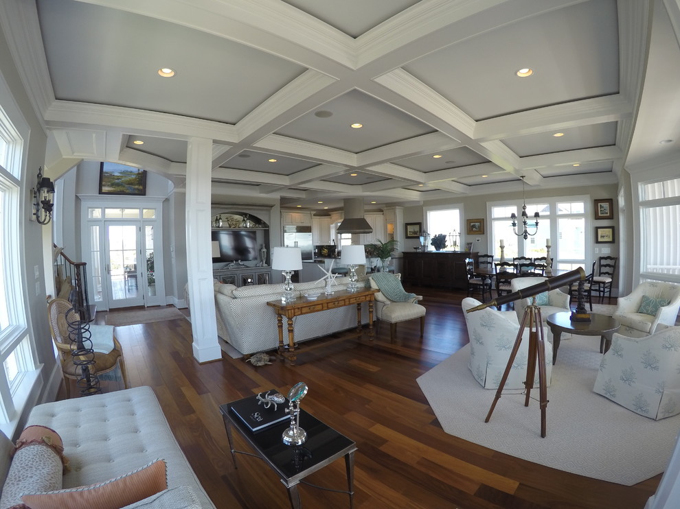 Diseño de sala de estar abierta costera de tamaño medio sin chimenea y televisor con paredes beige y suelo de madera en tonos medios