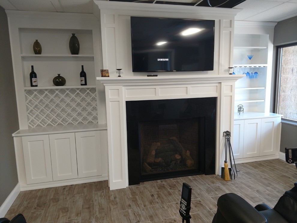 Photo of a medium sized classic games room in New York with grey walls, porcelain flooring, a standard fireplace, a wooden fireplace surround, a wall mounted tv and brown floors.