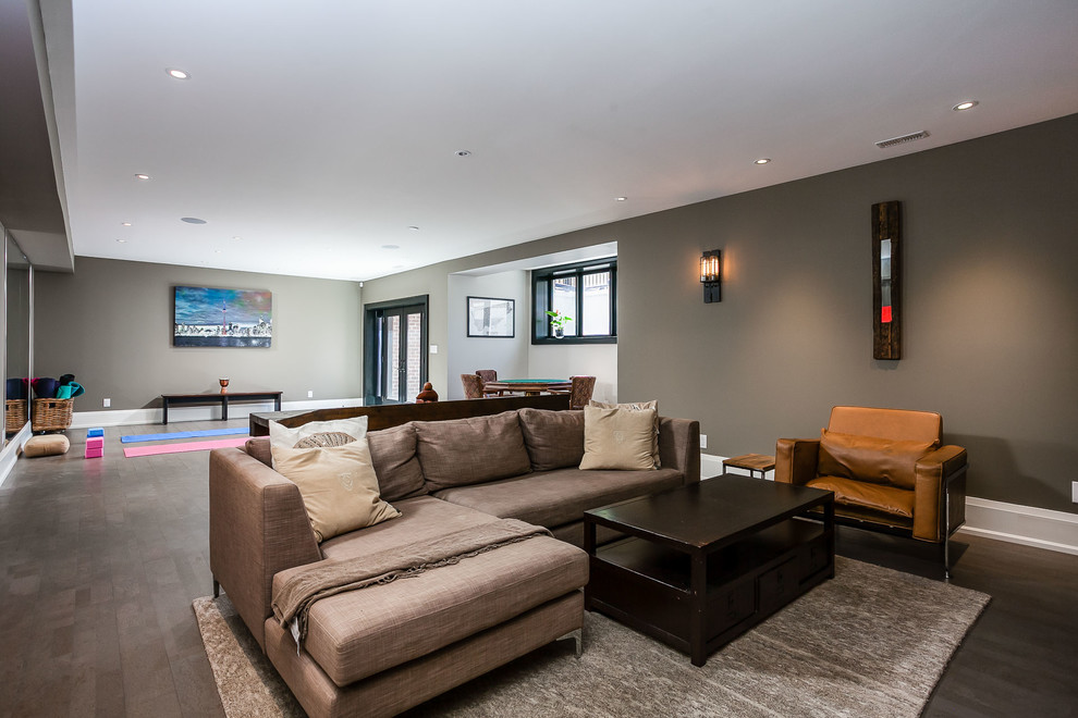 Mittelgroßes, Offenes Modernes Wohnzimmer mit Hausbar, grauer Wandfarbe, Betonboden, Gaskamin, Kaminumrandung aus Beton, TV-Wand und grauem Boden in Toronto