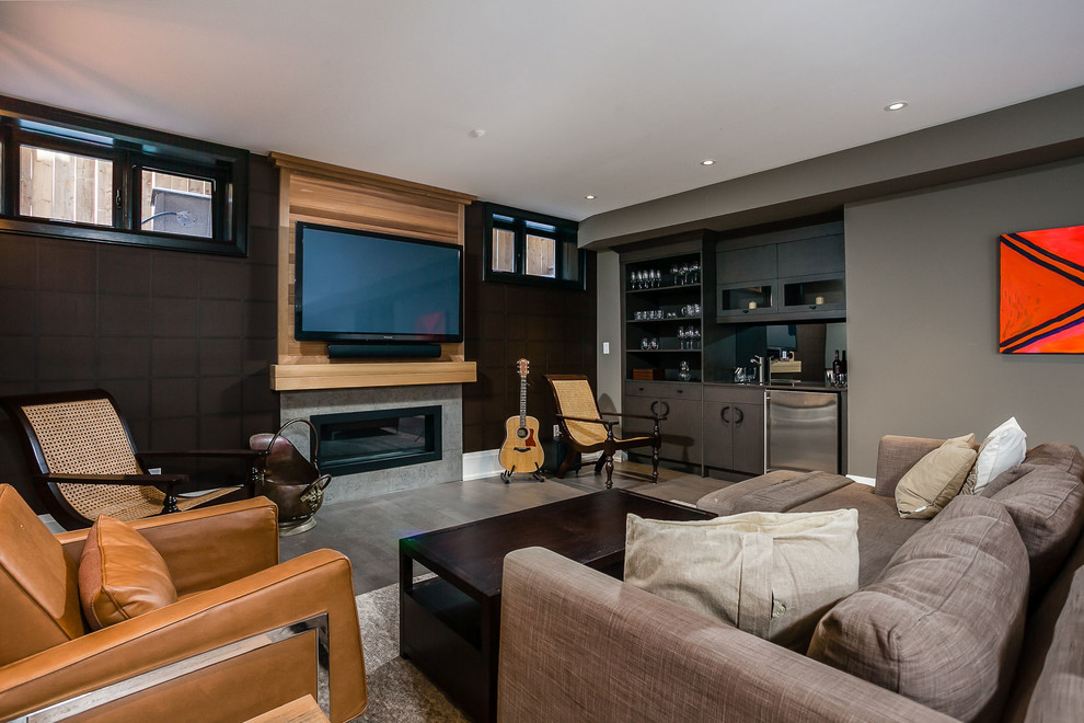 Imagen de sala de estar con barra de bar abierta contemporánea de tamaño medio con paredes grises, suelo de cemento, chimenea lineal, marco de chimenea de hormigón, televisor colgado en la pared y suelo gris
