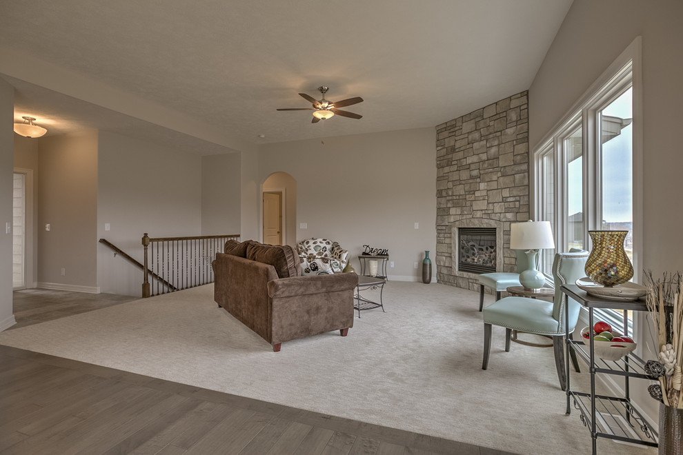 Foto de sala de estar abierta minimalista de tamaño medio con paredes grises, moqueta, chimenea de esquina, marco de chimenea de piedra y suelo beige