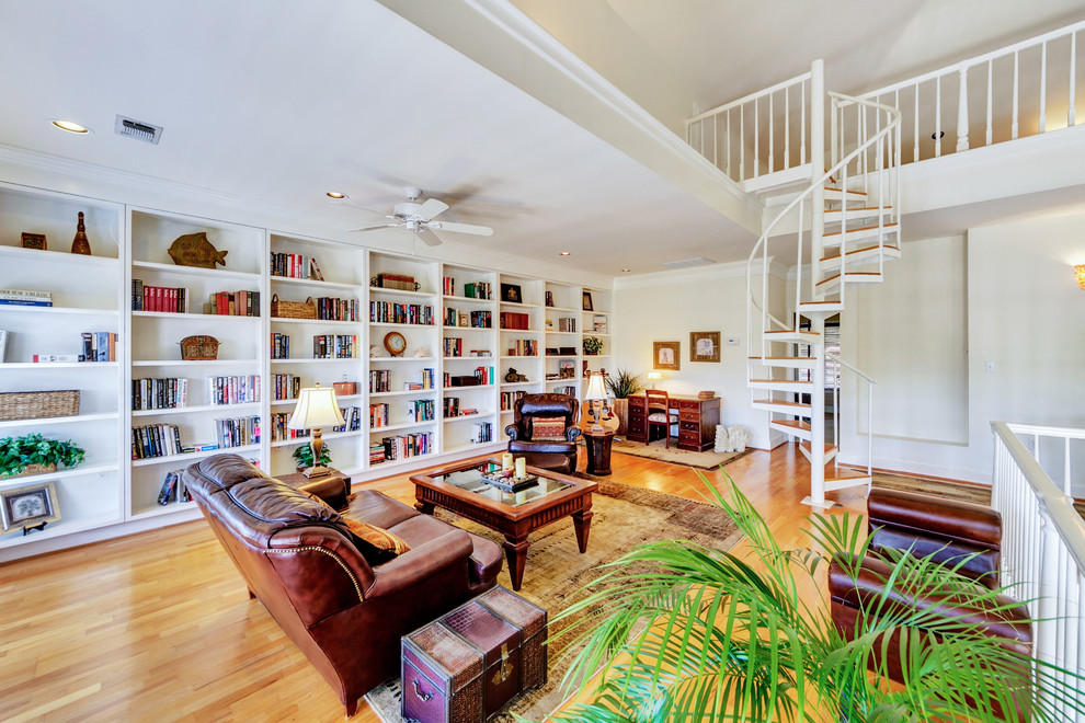 Elegant medium tone wood floor family room library photo in Miami with white walls, no fireplace and no tv