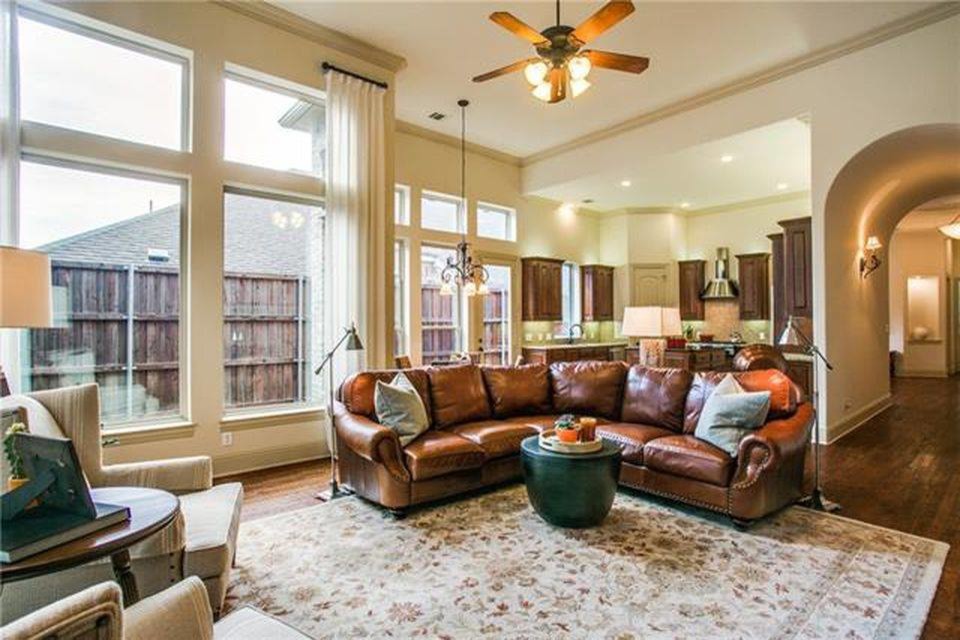 Mittelgroßes, Offenes Klassisches Wohnzimmer mit beiger Wandfarbe, braunem Holzboden, Kamin, Kaminumrandung aus Stein, Multimediawand und braunem Boden in Dallas