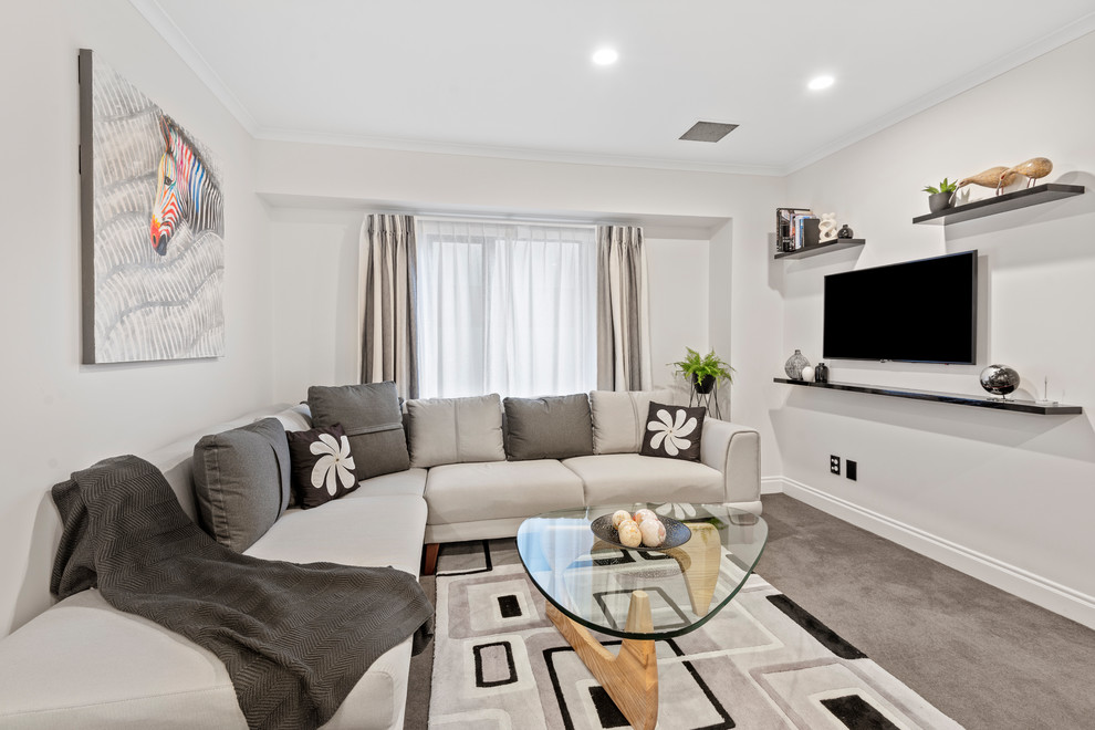 Abgetrenntes Modernes Wohnzimmer mit weißer Wandfarbe, Teppichboden, TV-Wand und grauem Boden in Auckland