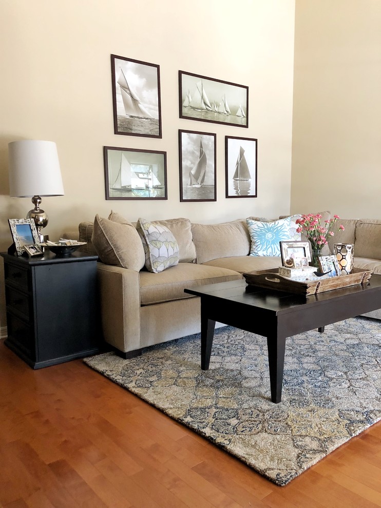 Imagen de sala de estar abierta tradicional renovada pequeña con paredes beige, suelo de madera en tonos medios, chimenea de esquina, marco de chimenea de ladrillo y televisor independiente