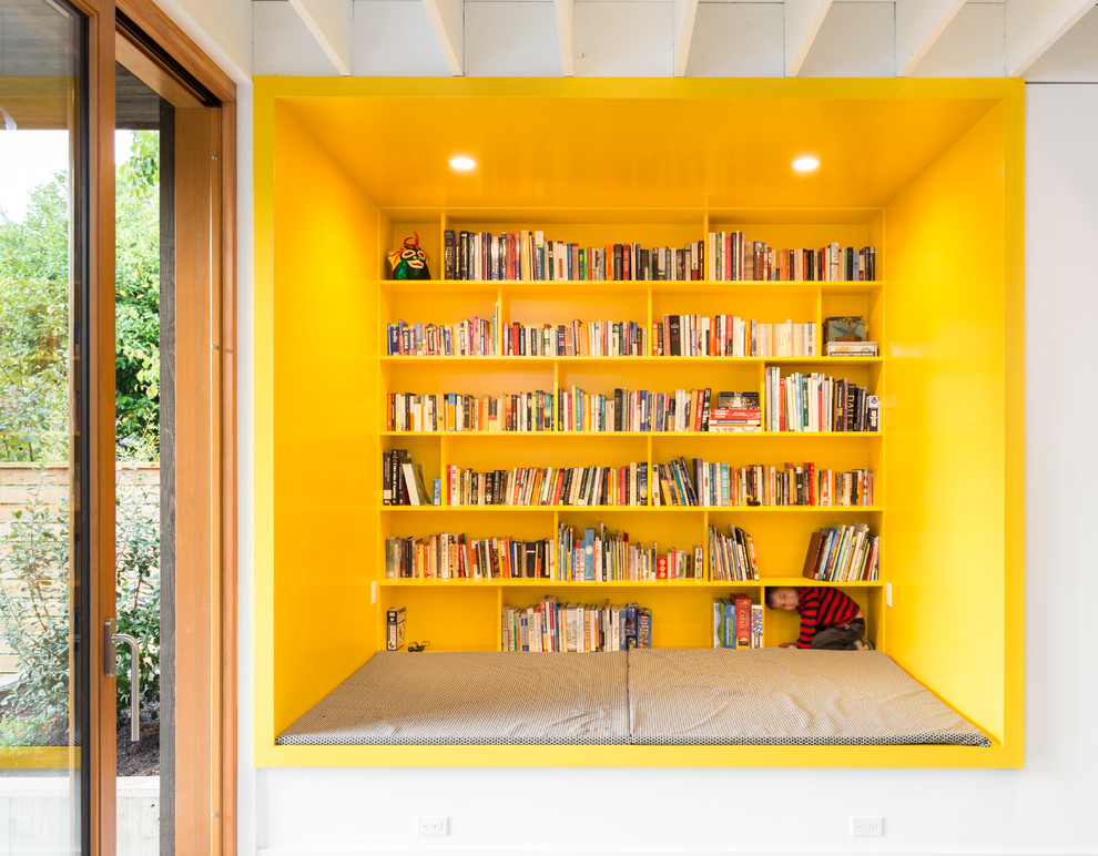 Cette image montre une salle de séjour design avec une bibliothèque ou un coin lecture et un mur jaune.