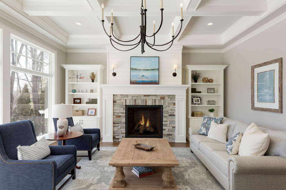 Foto de sala de estar abierta tradicional renovada grande con paredes grises, suelo de madera en tonos medios, todas las chimeneas, marco de chimenea de piedra y suelo marrón