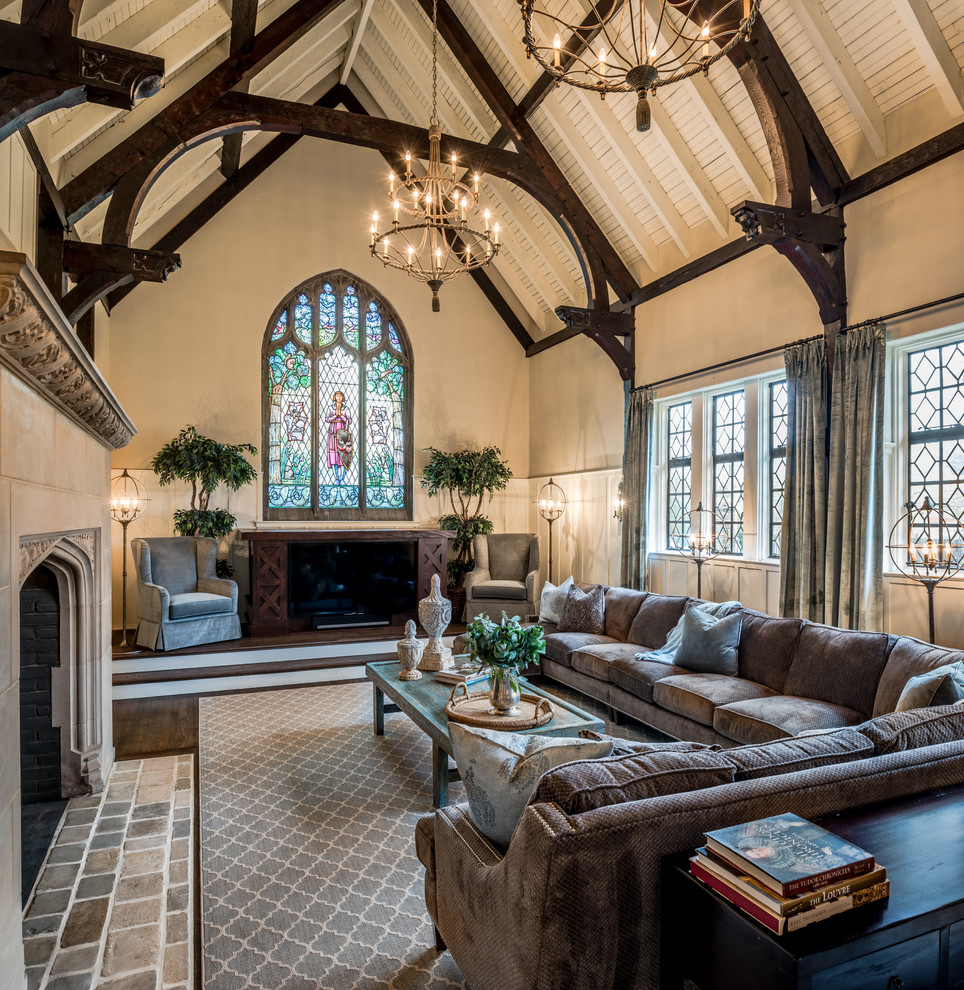 Imagen de sala de estar tradicional grande con paredes grises, suelo de madera oscura, todas las chimeneas, marco de chimenea de piedra y pared multimedia