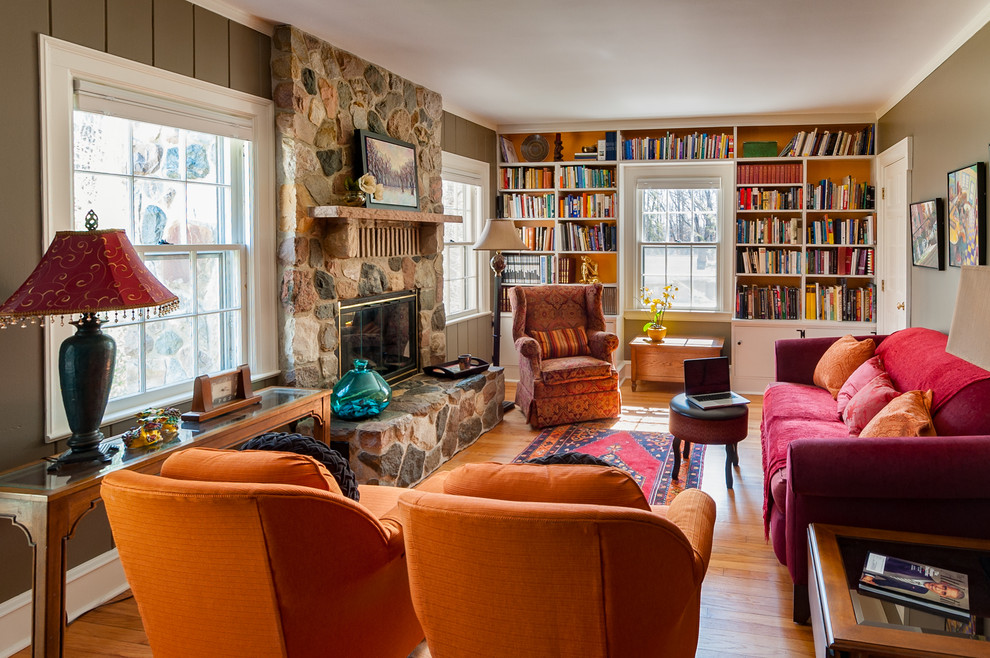 Idées déco pour une salle de séjour éclectique de taille moyenne et fermée avec une bibliothèque ou un coin lecture, un mur beige, un sol en bois brun, une cheminée standard et un manteau de cheminée en pierre.
